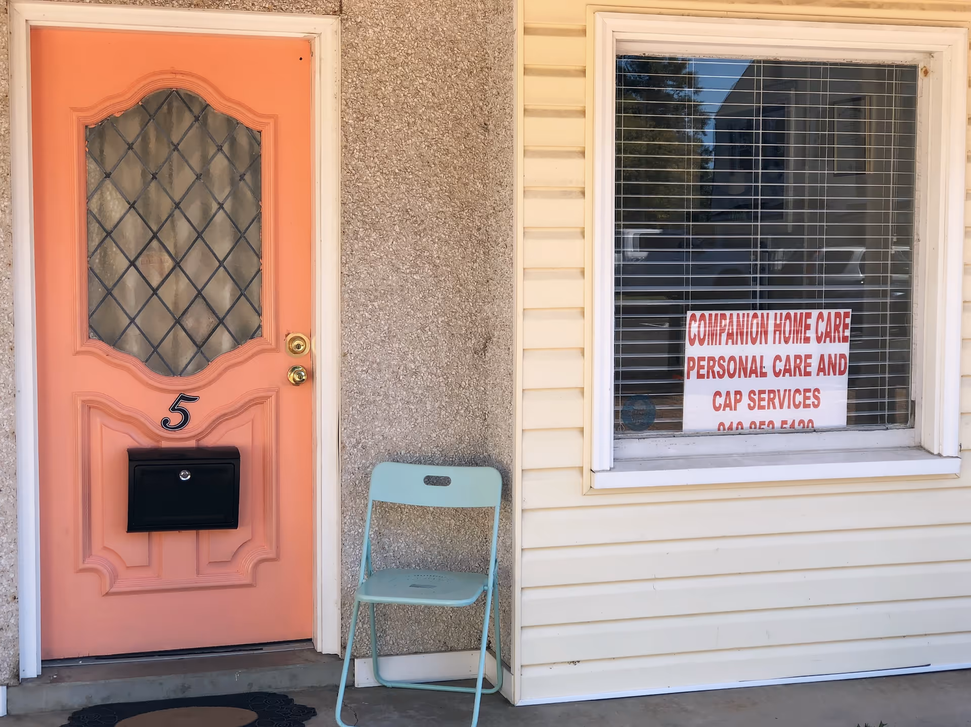 Pink front door with number 5, mint chair, and window sign for Companion Home Care.