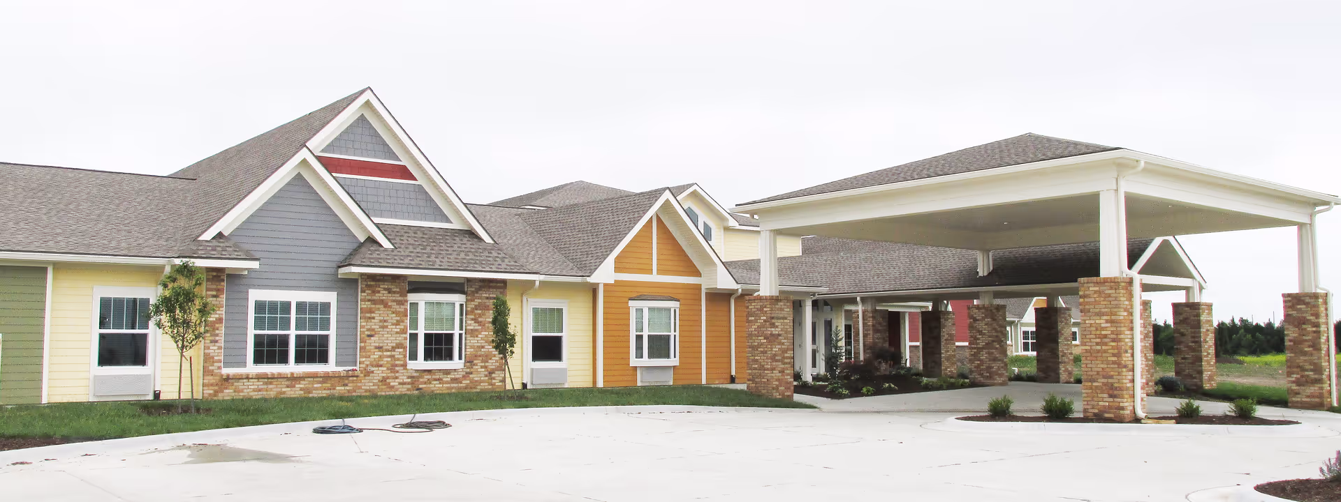 Colorful single-story senior living building with a covered entry and brick columns.