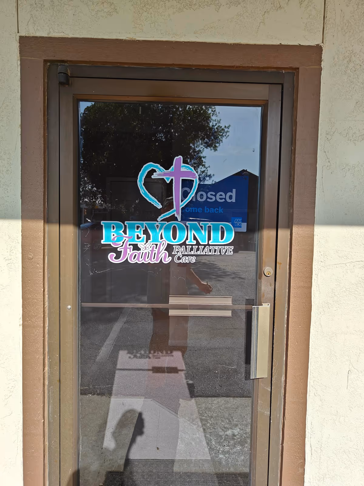 Glass door displays Beyond Faith Palliative Care logo at facility entrance.