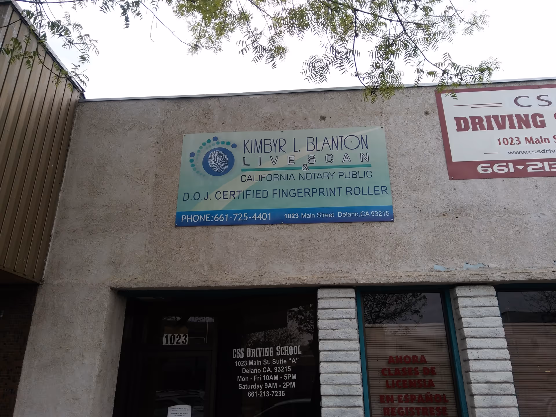 Exterior of a building façade with a blue LiveScan sign and driving school advertisement.