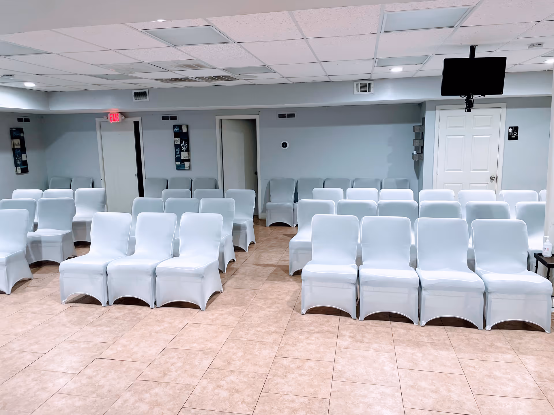 Rows of light blue covered chairs in a spacious, empty facility meeting room.