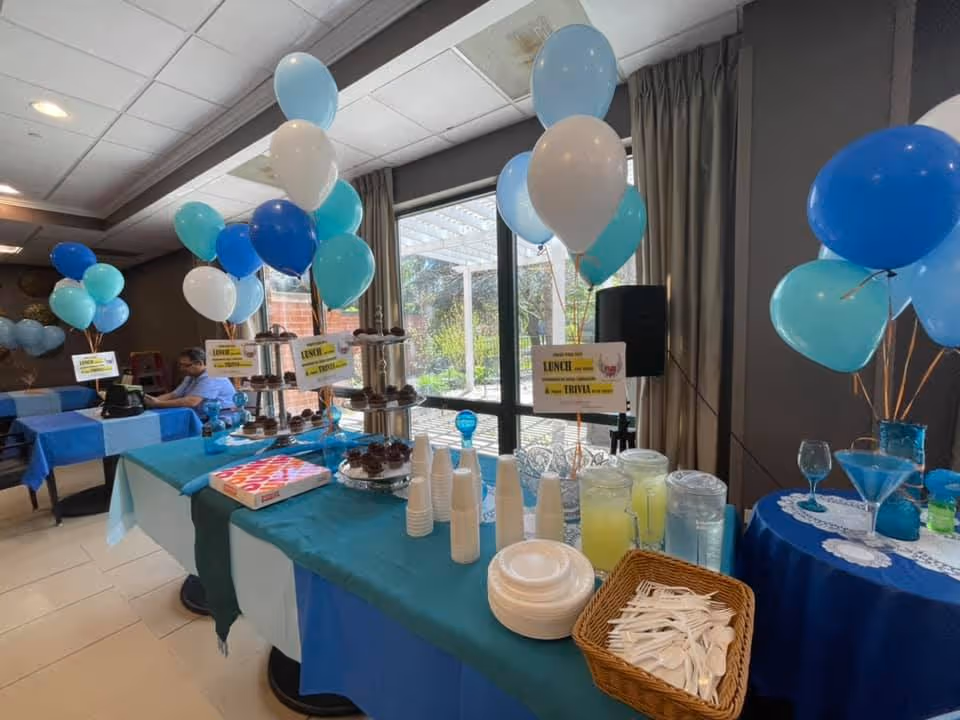 Interior dining area decorated with balloons and a long buffet table.