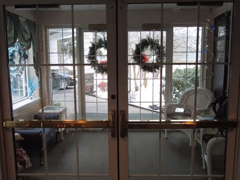 Glass double doors open to a cozy enclosed porch with wicker seating and holiday wreaths visible.