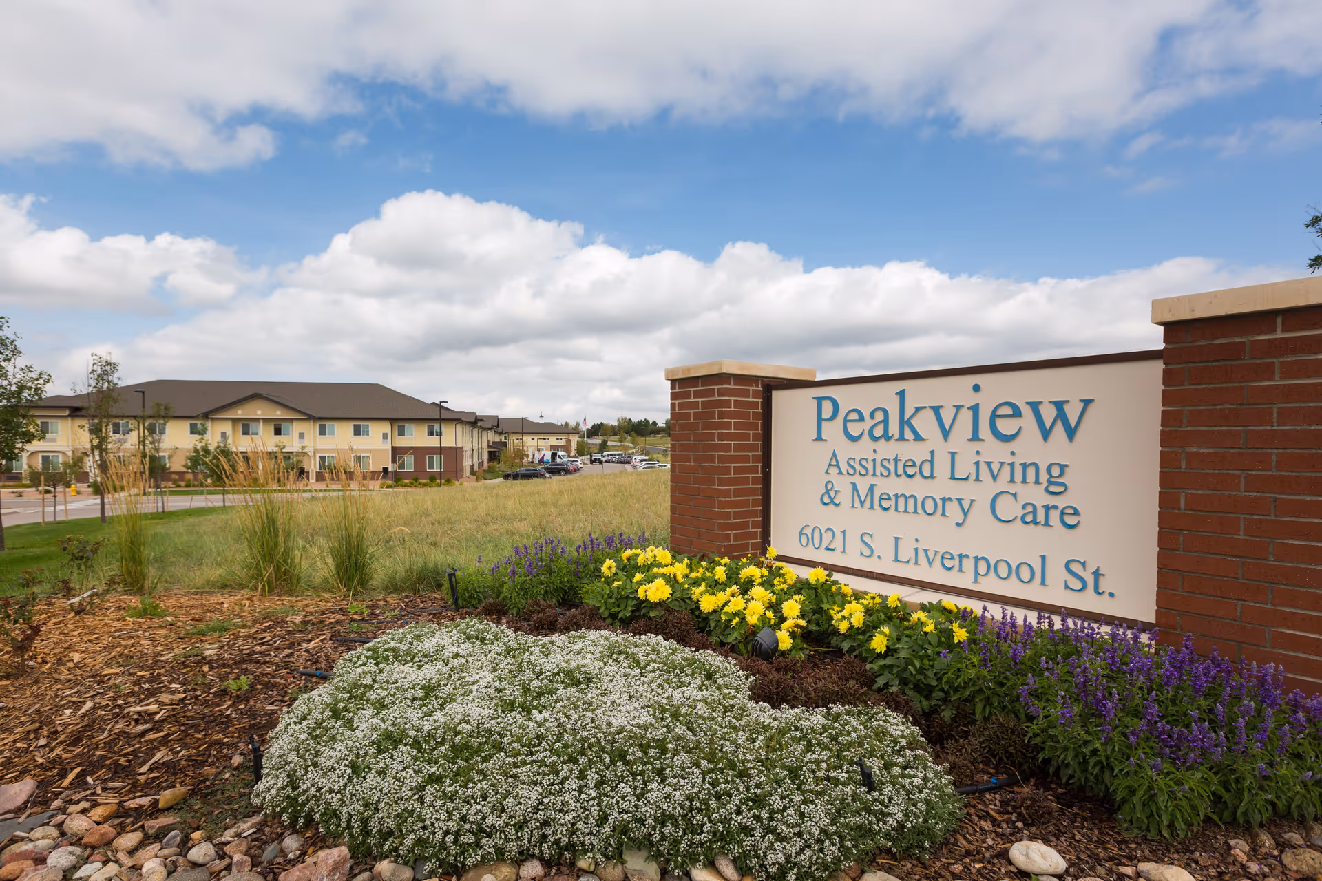 Exterior view of Peakview Assisted Living sign with landscaped beds and building in the background.