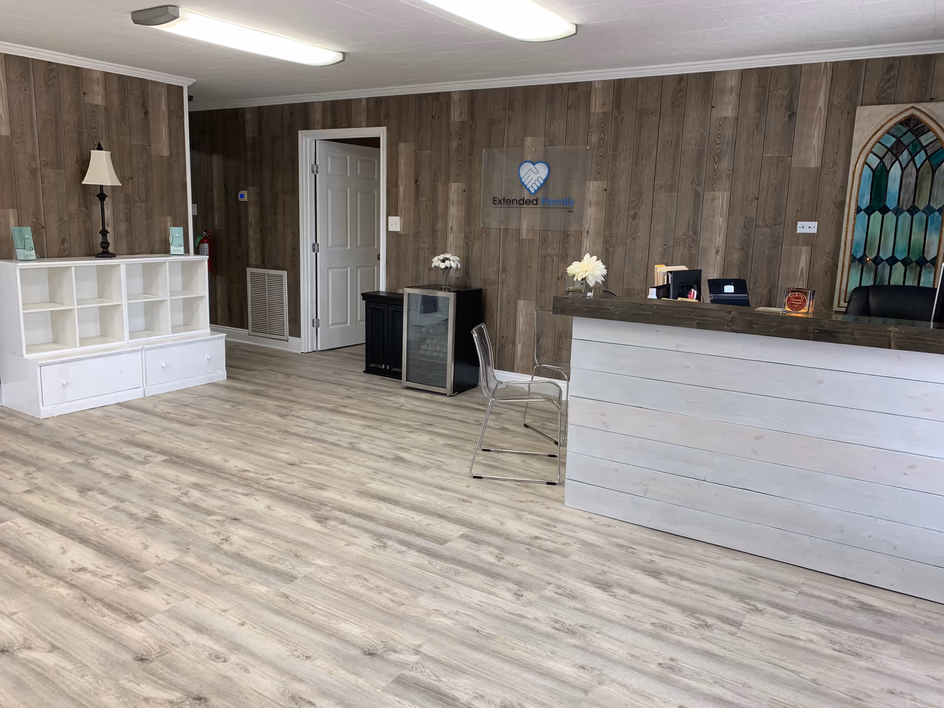 Reception area with wooden panel walls, white desk, and minimal seating in facility lobby.