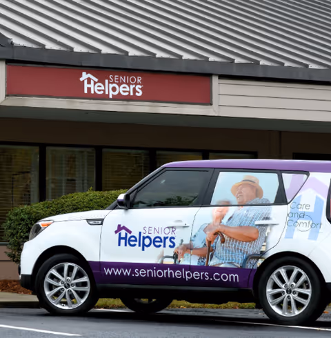 Exterior view of Senior Helpers facility with a branded van parked in front.