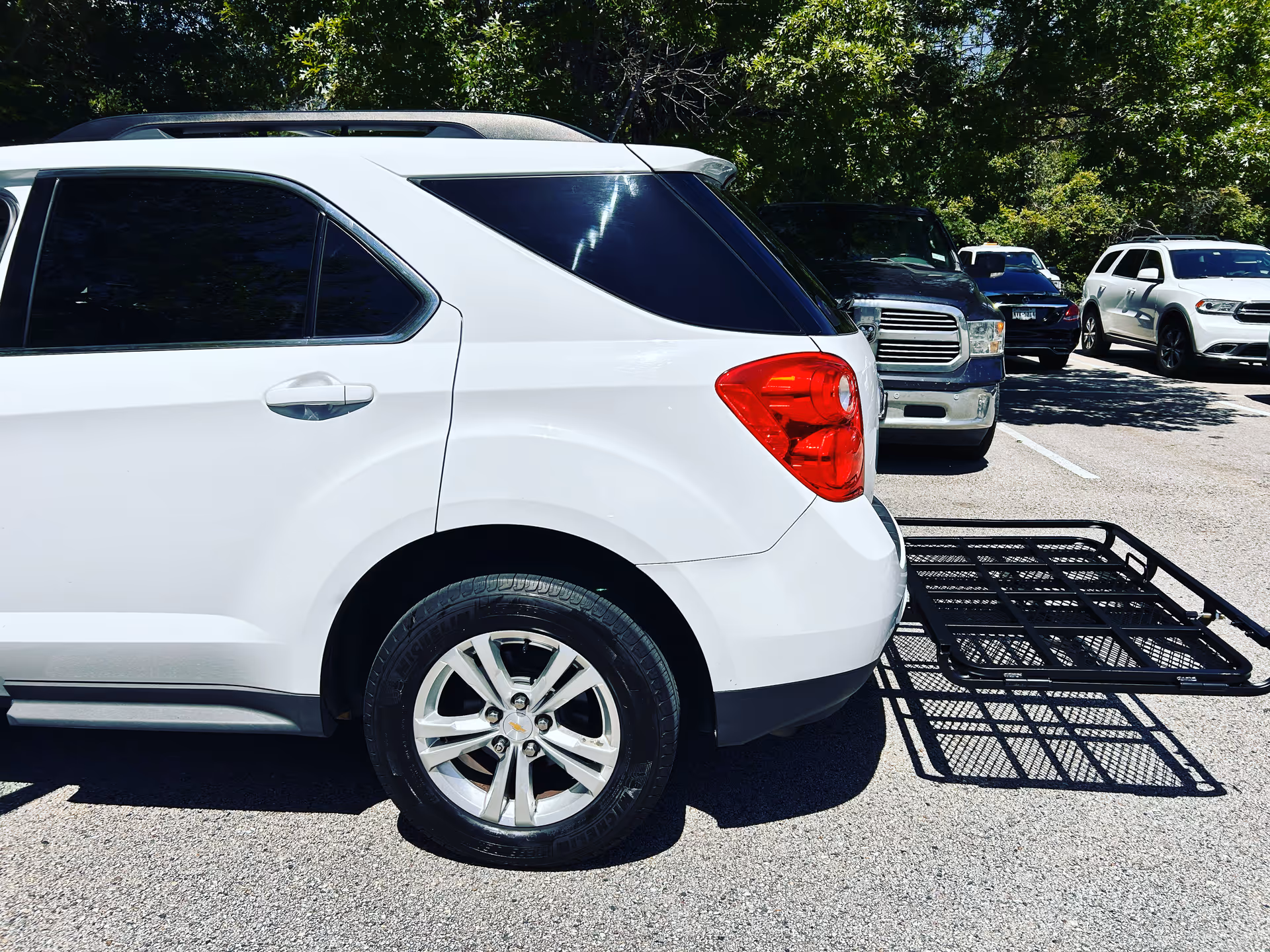 White SUV with a trailer hitch parked in a sunny outdoor parking lot.