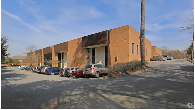 Exterior view of a brick facility with a parking lot and parked cars.
