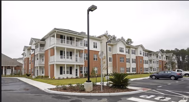 Exterior view of St. Anthony's Gardens senior living building with balconies and parked cars.