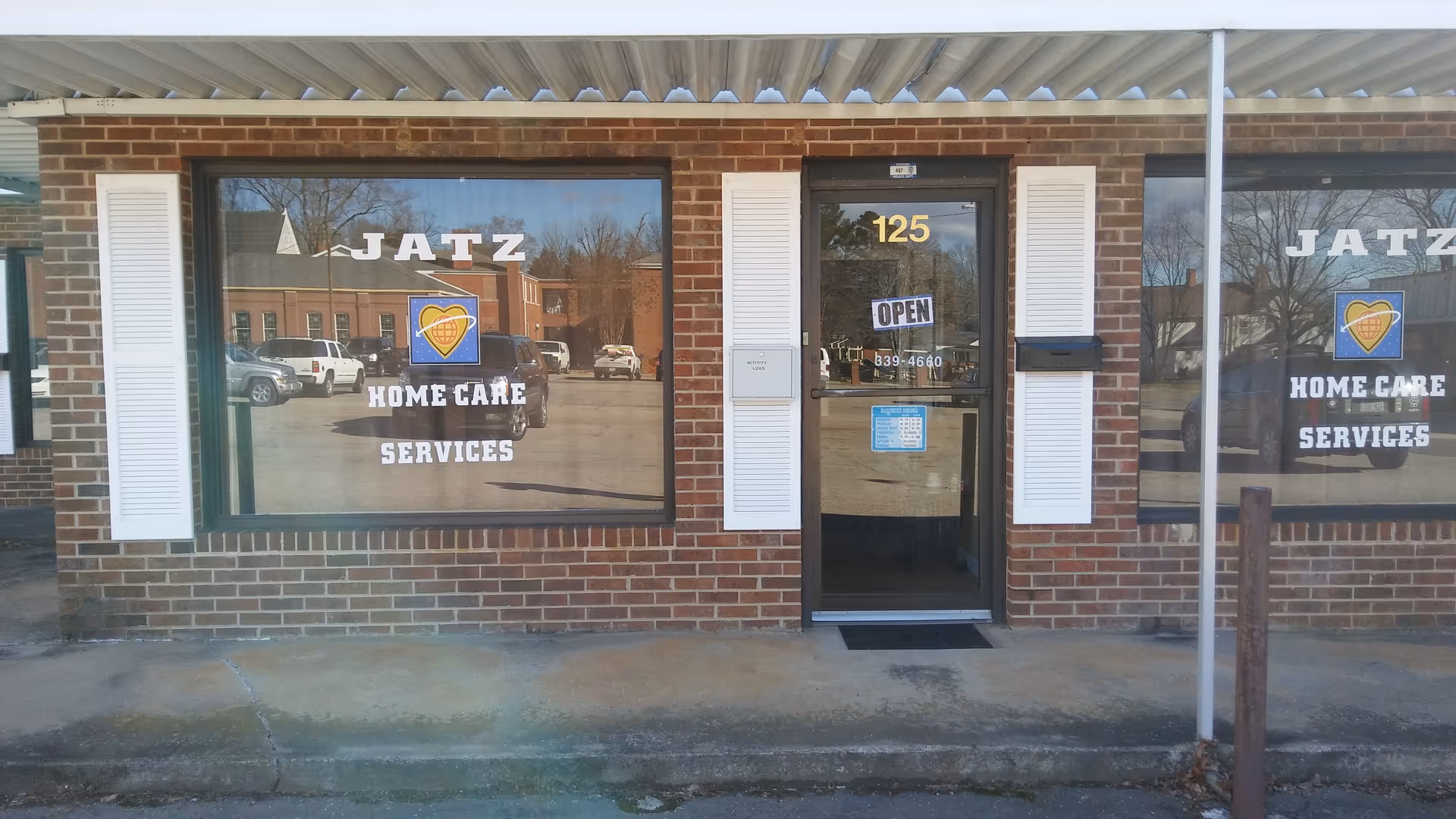 Brick storefront with large windows reading Jatz Home Care Services and a centered door.