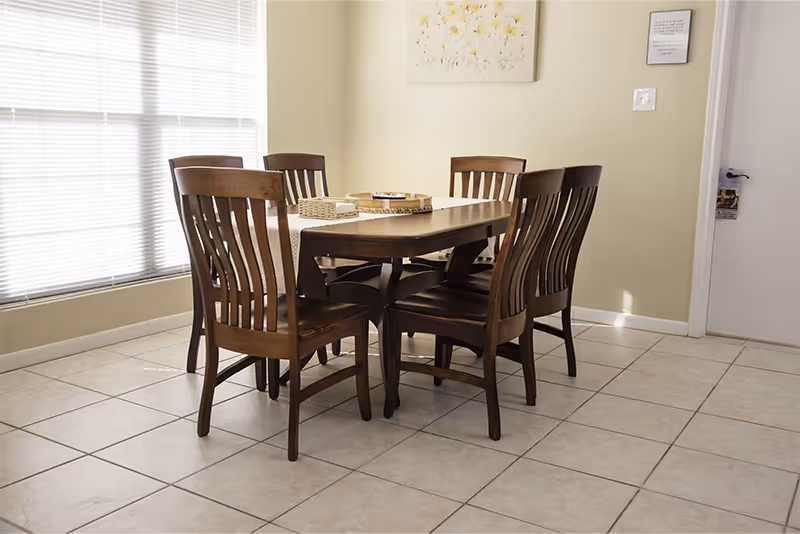 Wood dining table with six chairs in a bright, tiled dining area.