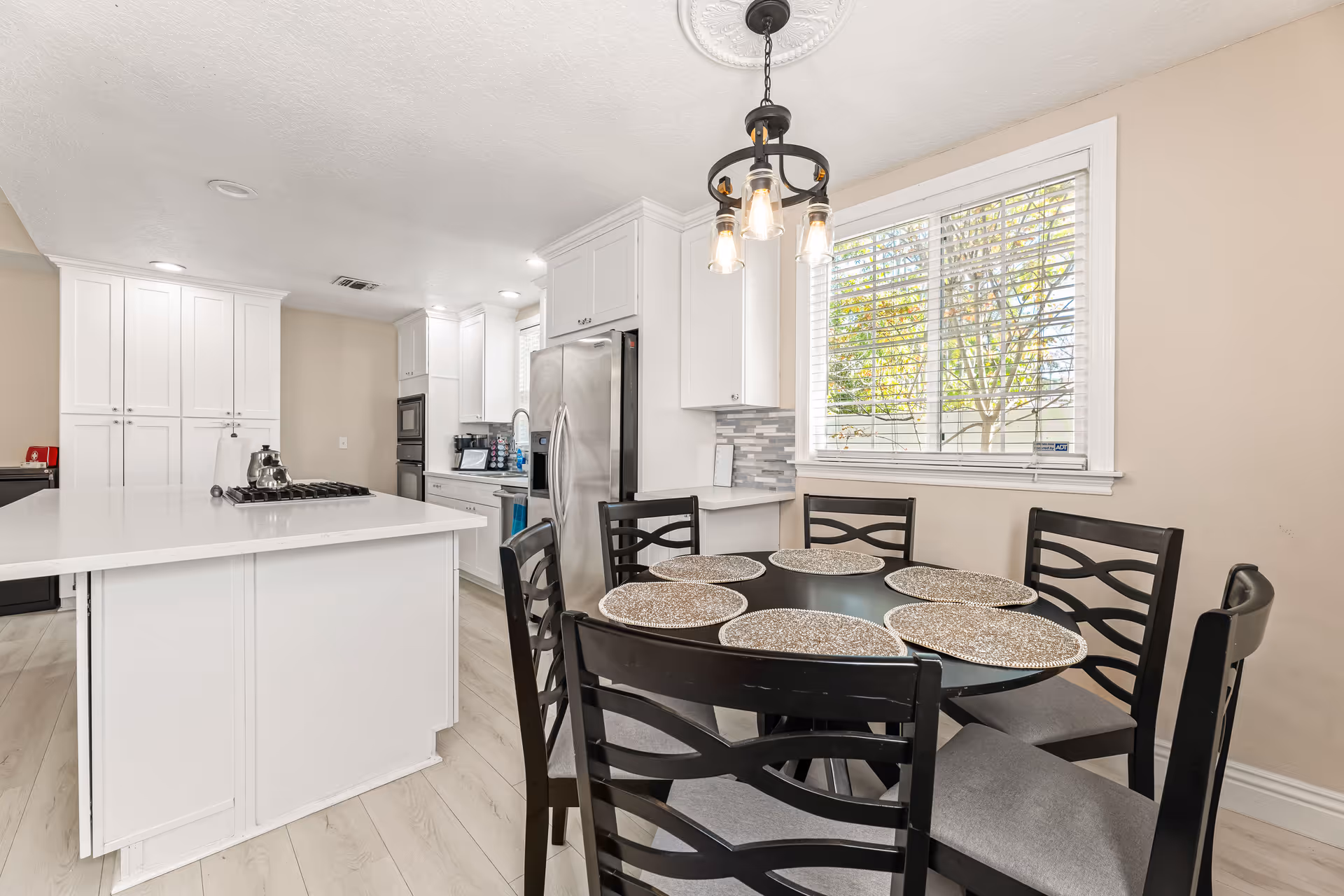 Bright white kitchen with island, stainless appliances, and a dining table.