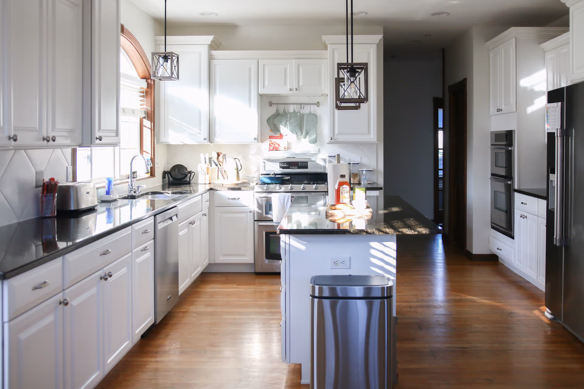 Bright white kitchen with island, stainless appliances, and wooden floors.