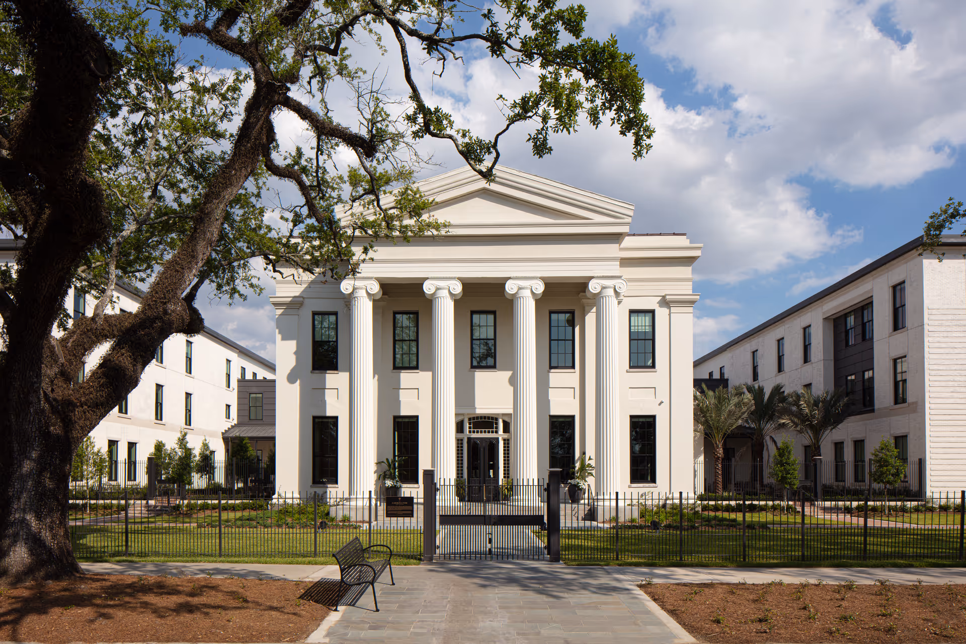A grand neoclassical front of a senior living campus with columns and a gated entrance.