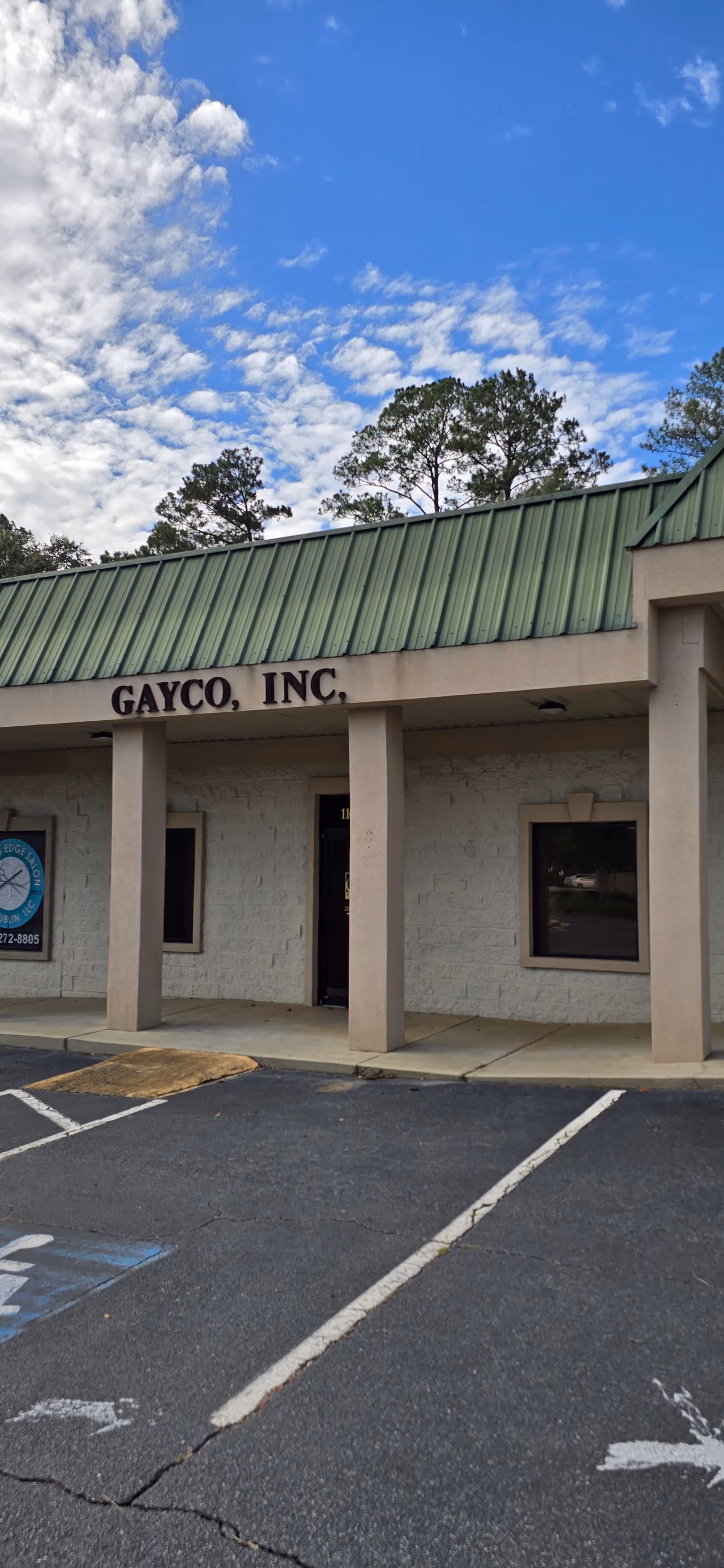 Exterior view of a beige building with a green metal roof and GAYCO, INC sign.