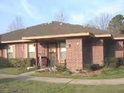 A single-story brick senior living facility with a covered entrance and manicured landscaping.