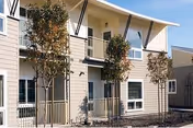 Exterior view of a two-story Casa Grande Senior Apartments building with balconies and small trees.