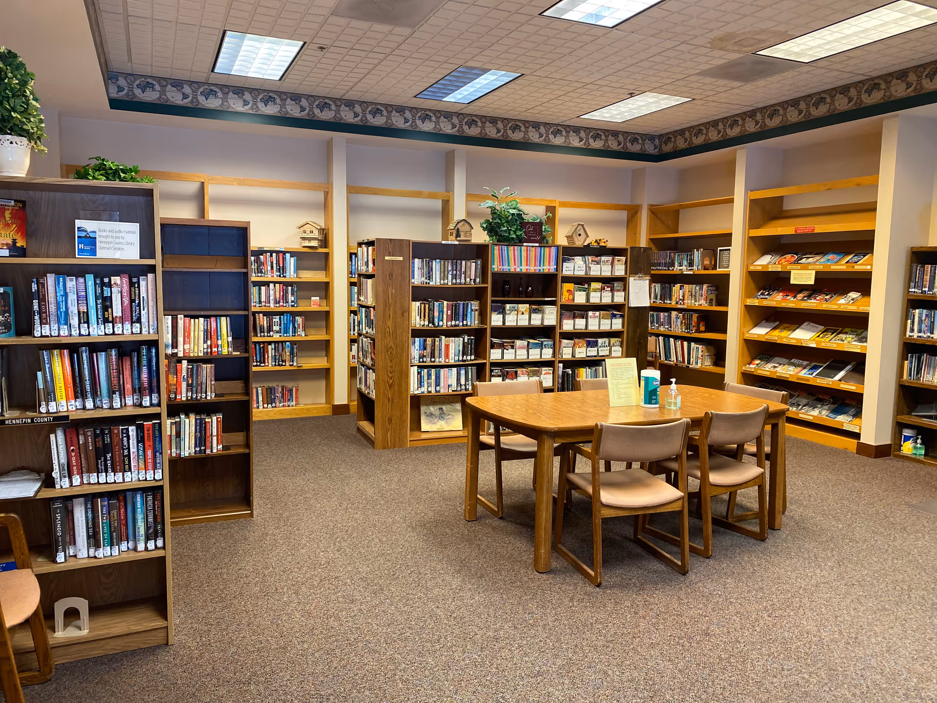 Library inside Covenant Living of Golden Valley with bookshelves, tables, and chairs.