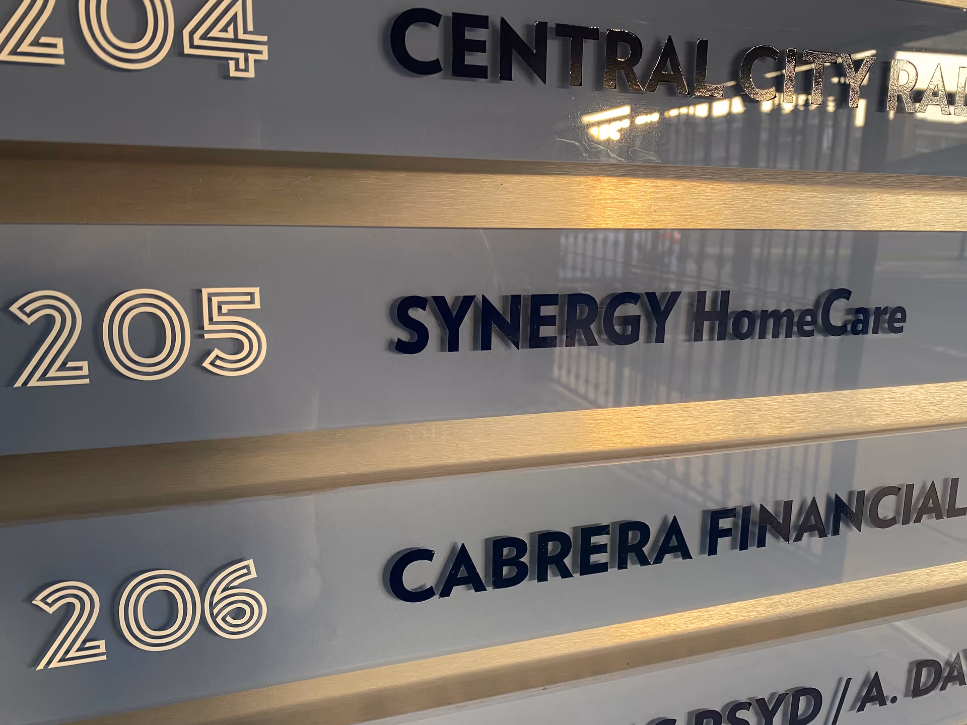 Exterior signboard displaying SYNERGY HomeCare and suite numbers 204-206.