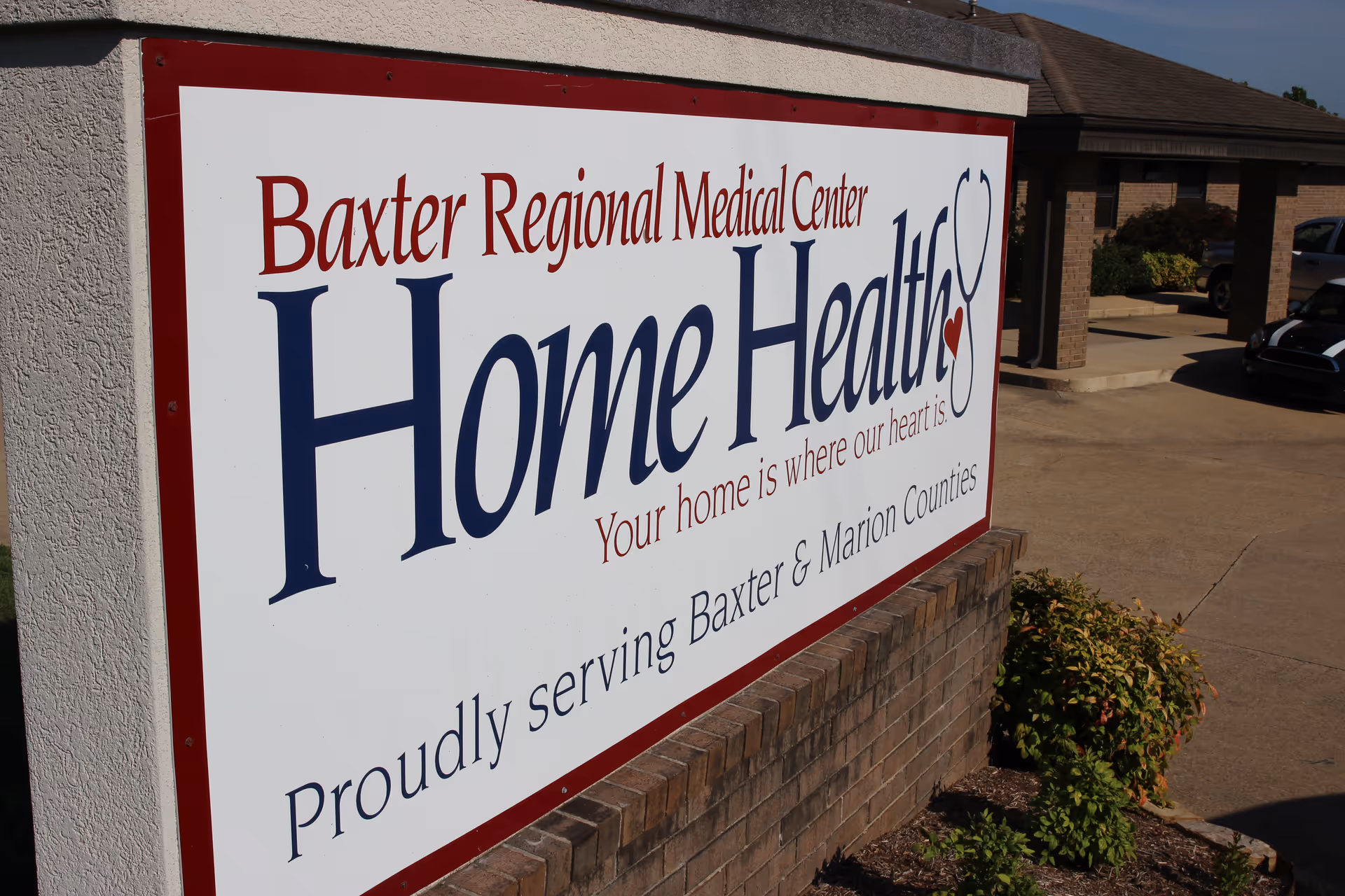 Large outdoor sign for Baxter Regional Medical Center Home Health on brick exterior wall.