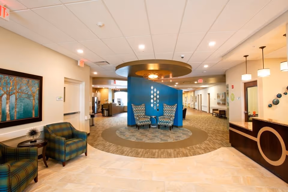 Senior living facility lobby with teal wall, circular seating area and reception desk.