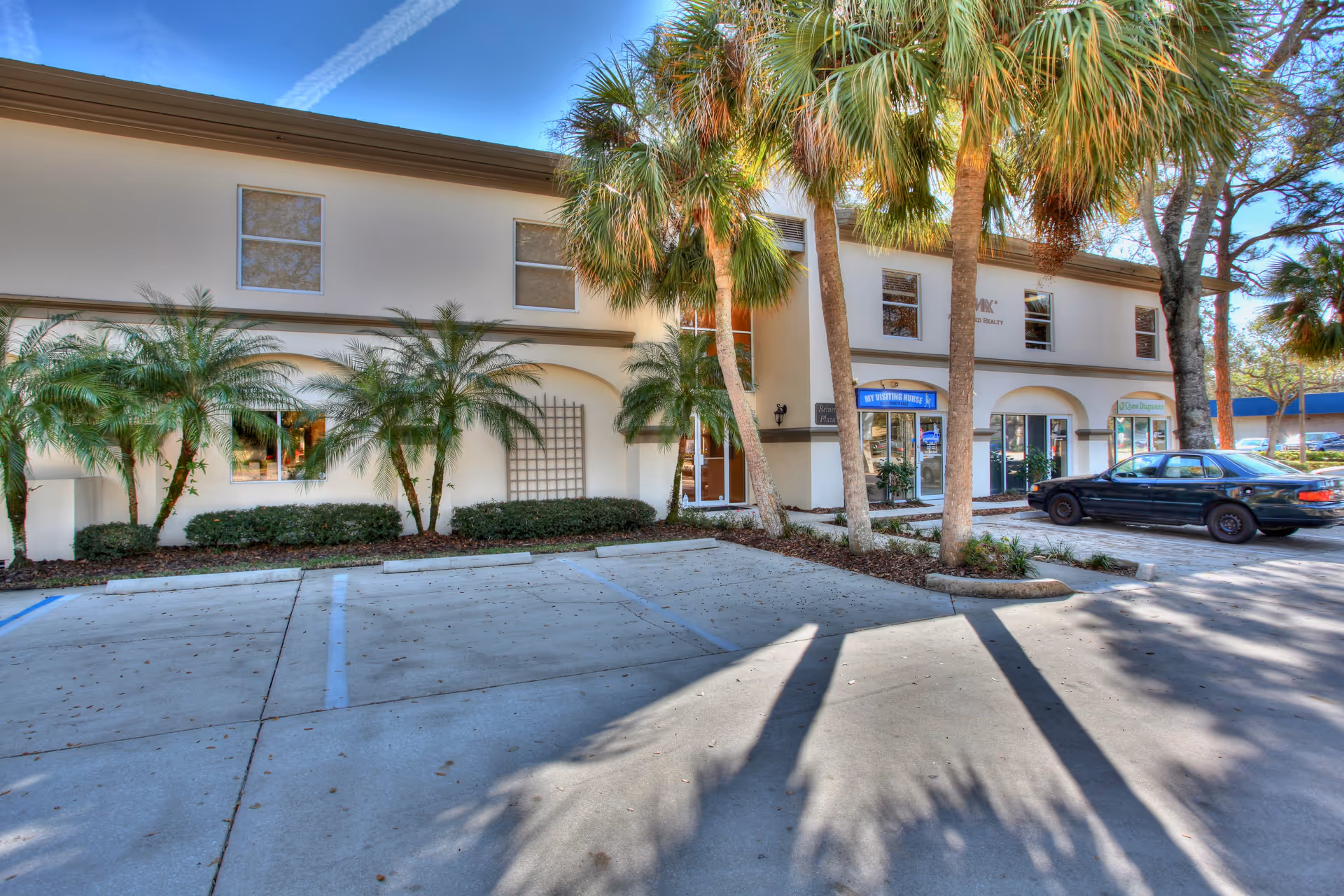 Exterior of My Visiting Nurse facility with palm trees, shrubs, and parked car.