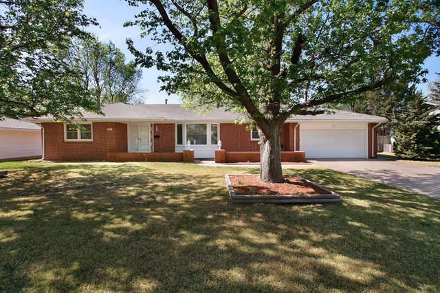 Single-story brick senior living building with a driveway, large tree, and front entrance.