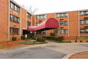 Brick apartment building with a curved red entrance canopy.