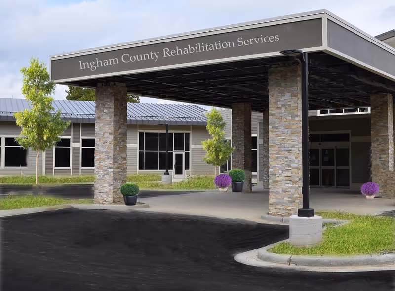 Front entrance of a rehabilitation facility with stone columns and a covered drop-off.