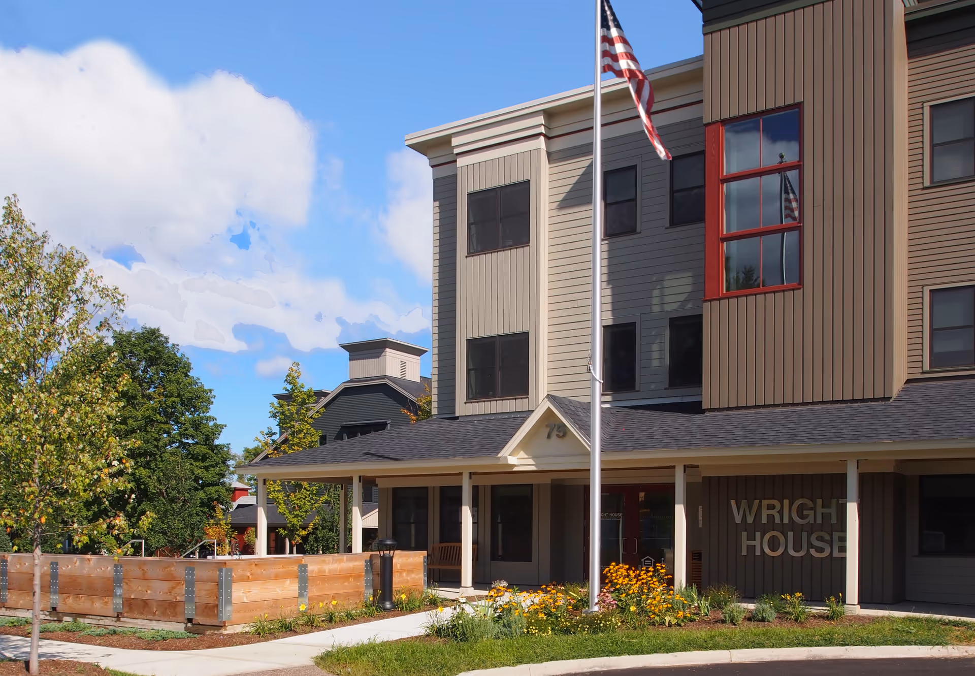Exterior view of Wright House, a senior living facility, with flagpole and landscaped frontage.