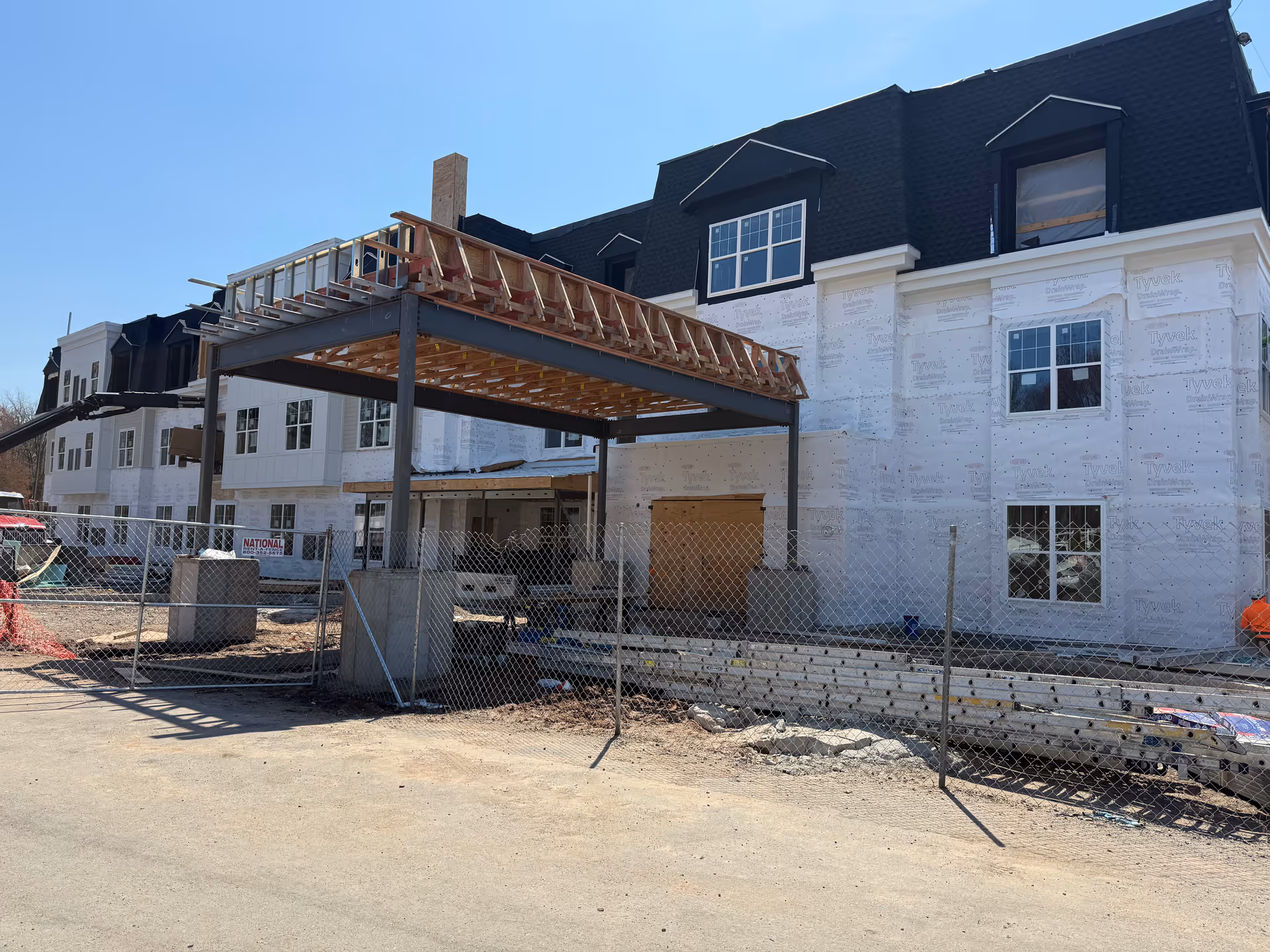 Under-construction senior living facility with exposed framing and chain-link fence.