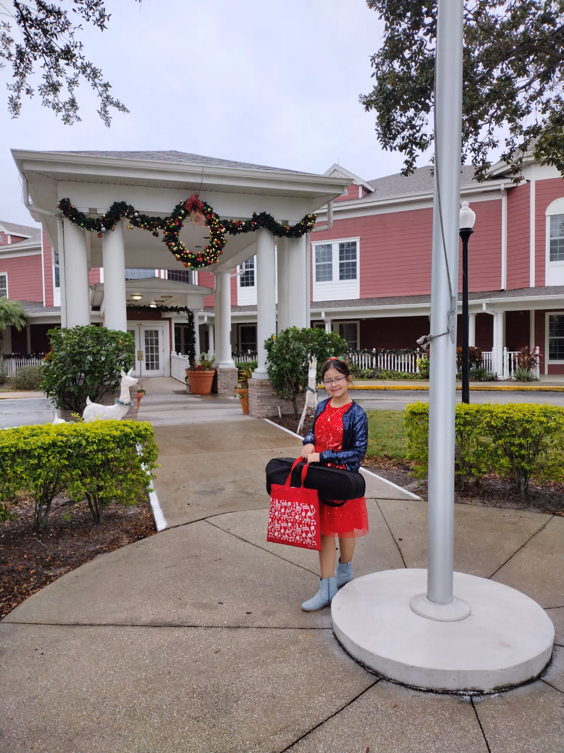 A girl stands outside Spring Hills Hunters Creek entrance with holiday garland and decorations.