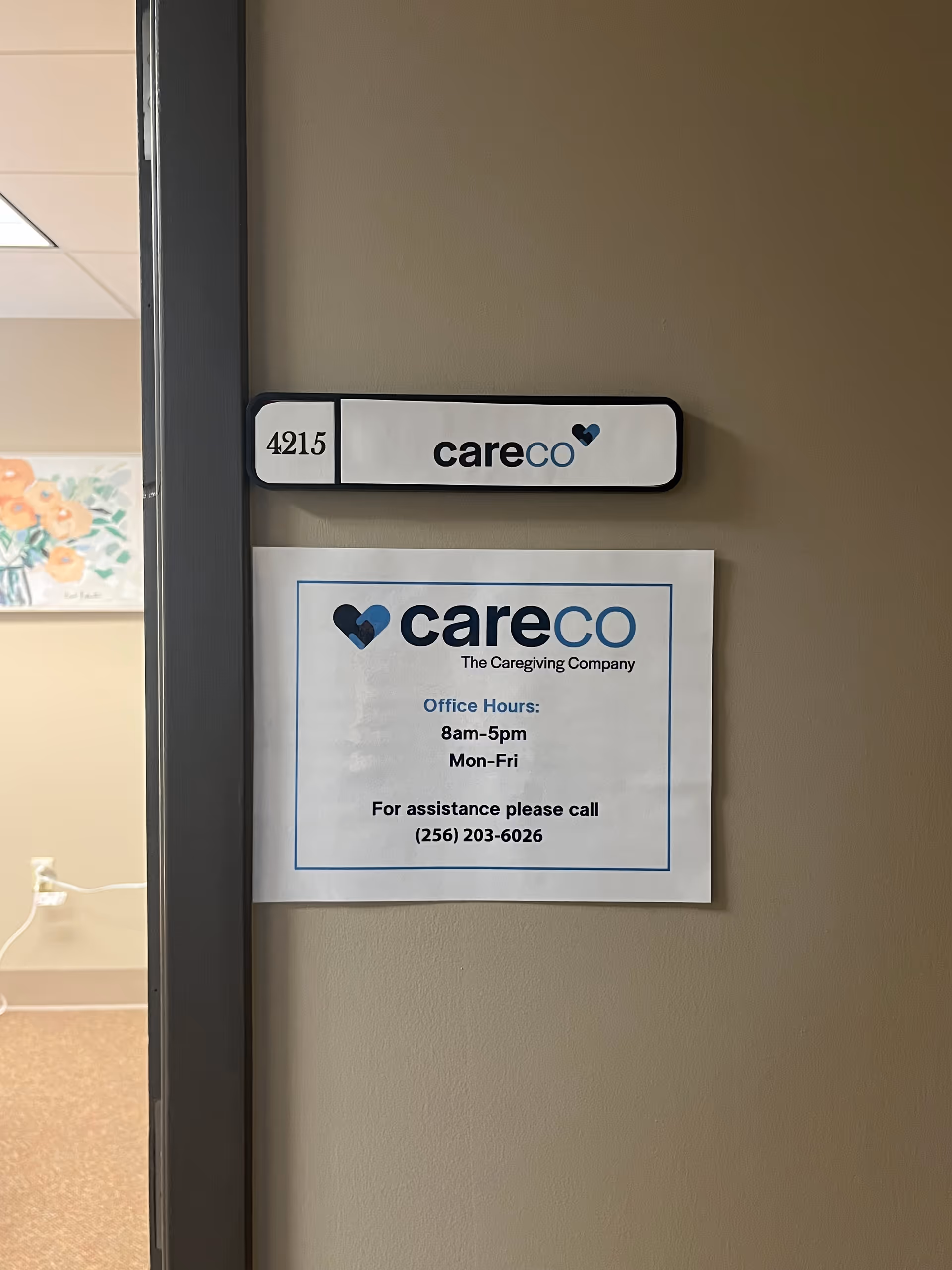 Interior hallway wall featuring 4215 sign and CareCo notice with office hours.