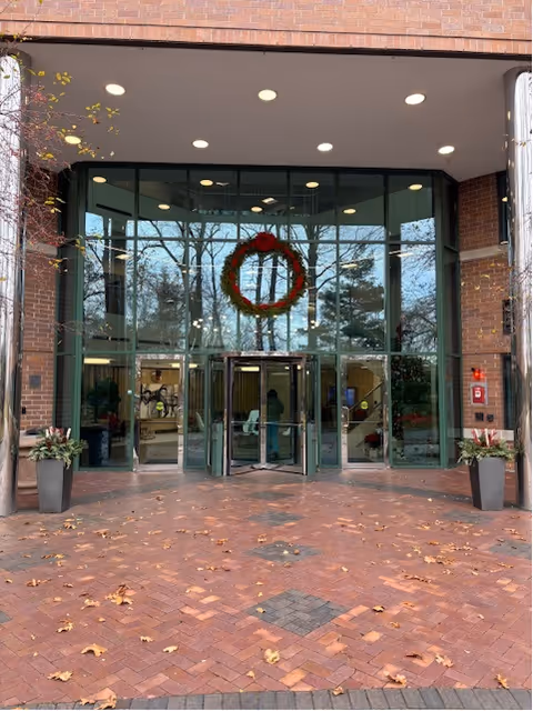 Front entrance of a brick building with glass doors and holiday wreath.