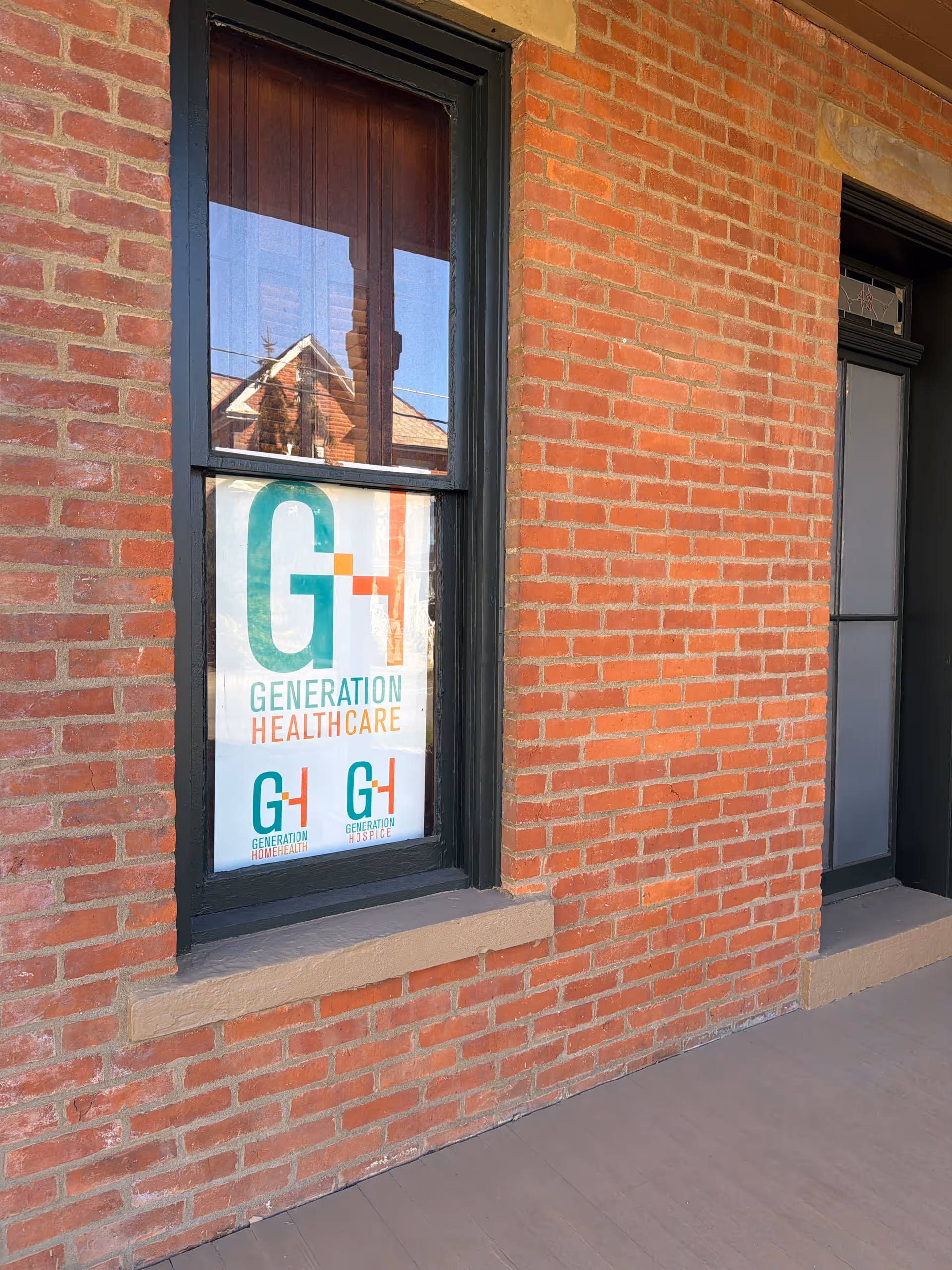 Brick building exterior with a window displaying a Generation HealthCare sign.