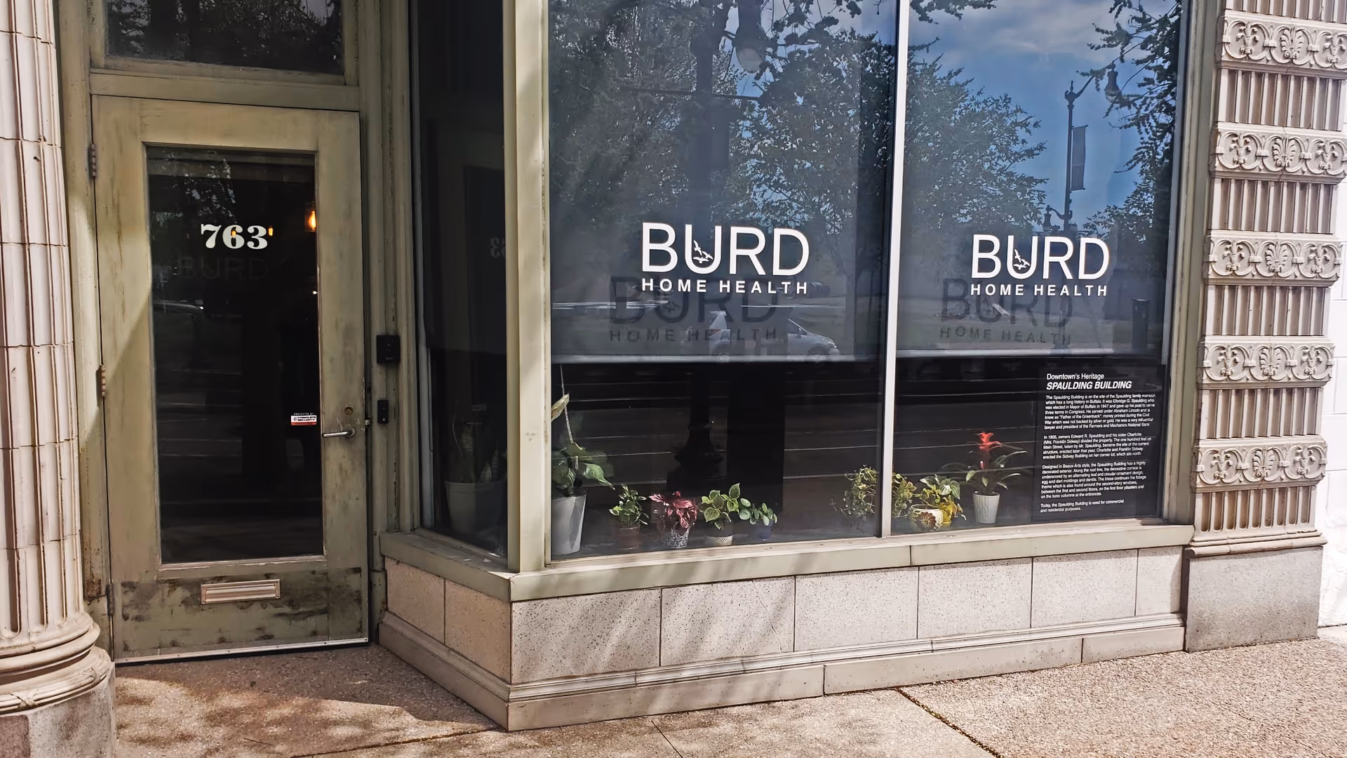 Storefront display for BURD Home Health with large windows and a green door.