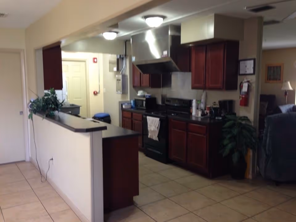 Open kitchen with dark wood cabinets, stainless steel appliances, and a dividing half-wall.