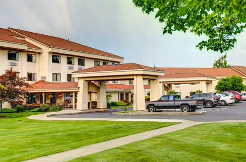 Exterior view of Grande Ronde Retirement Residence with covered entrance and parked cars.