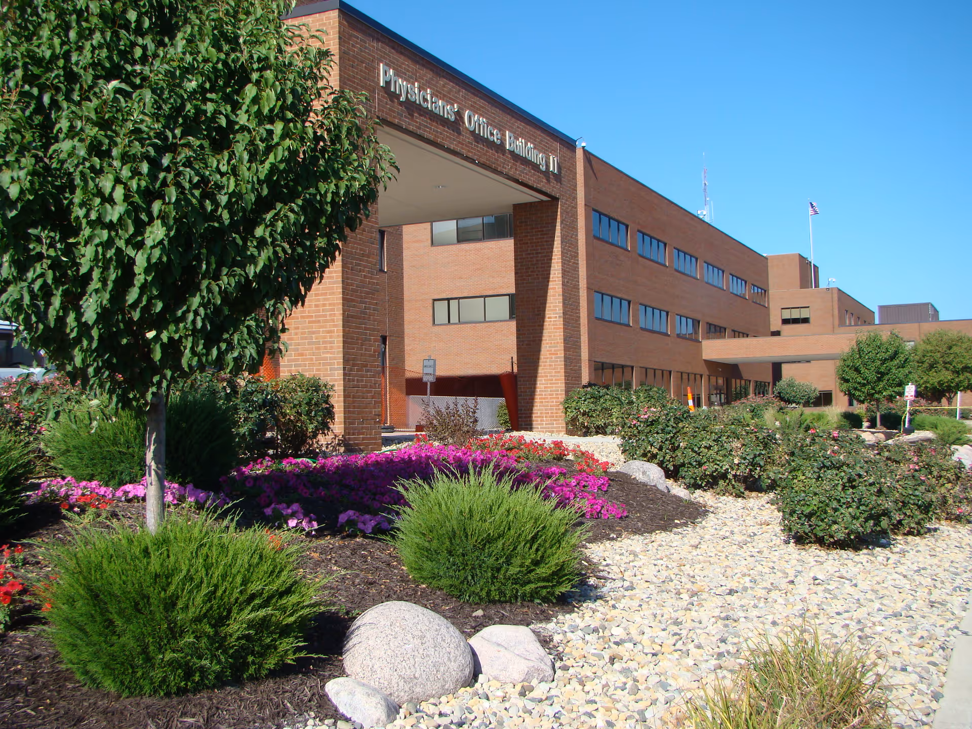 Brick physician's office building with landscaped foreground and bright blue sky.