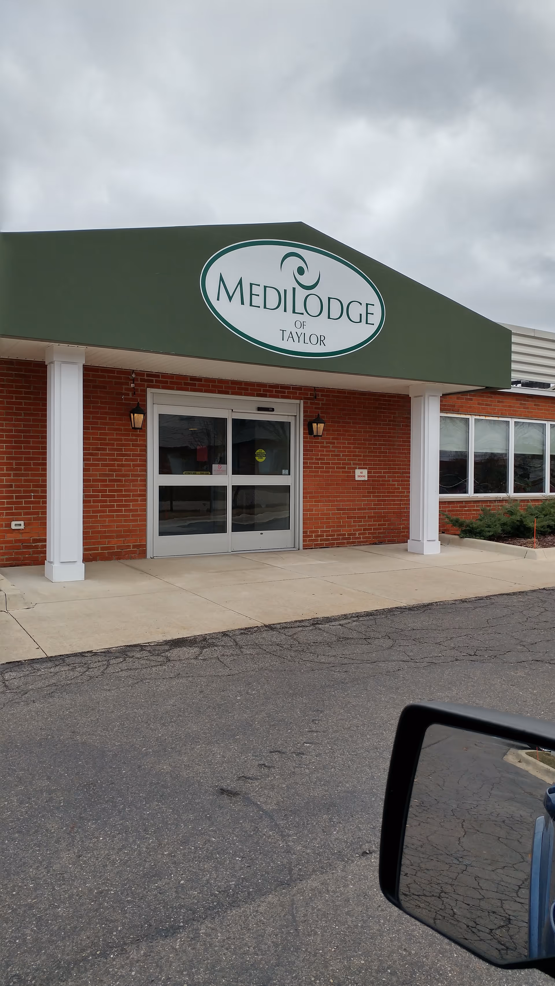 Exterior front of Medilodge of Taylor with green sign and brick facade.