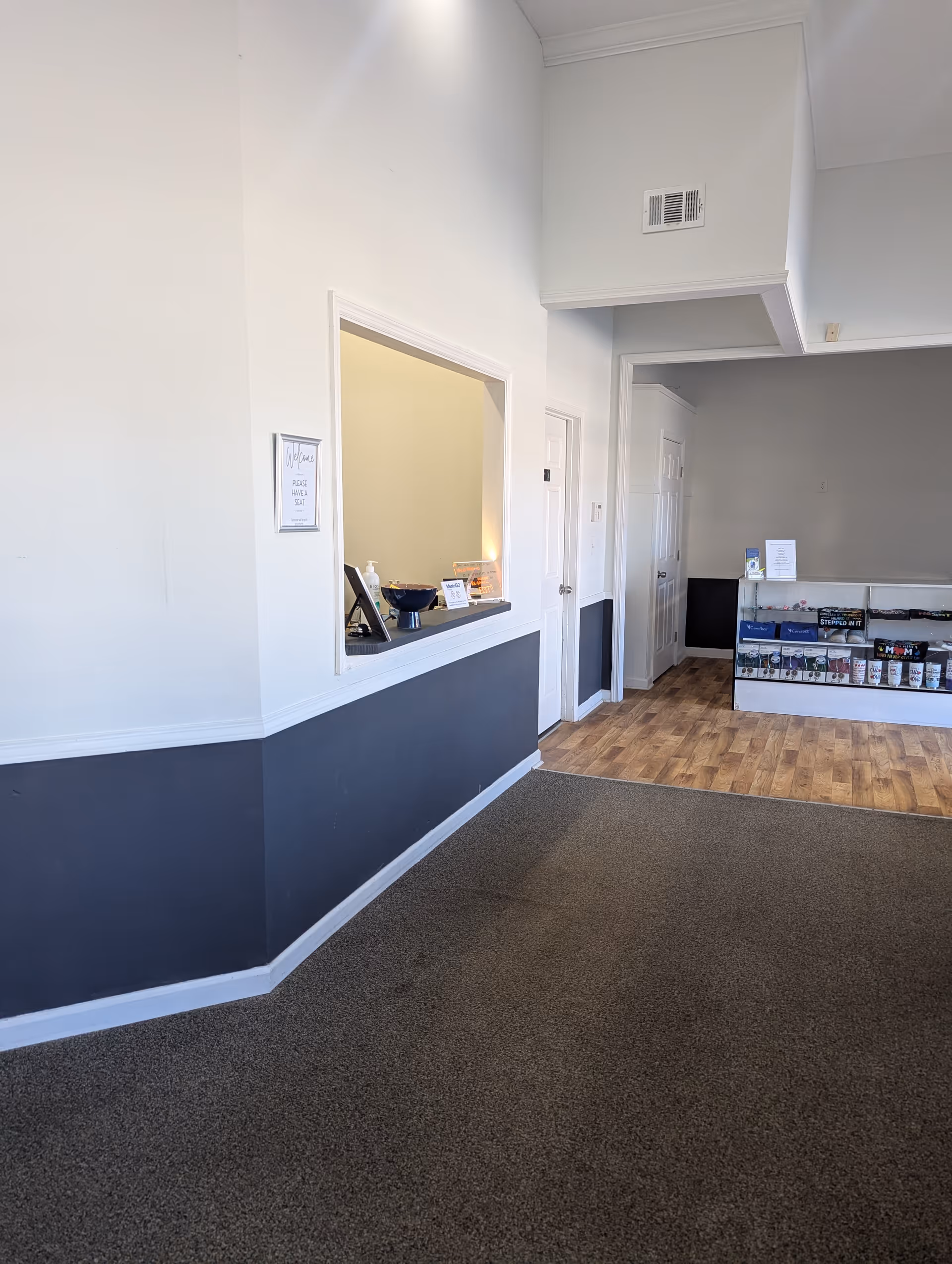 Interior of a senior facility lobby with a reception window and hallway to a display area.