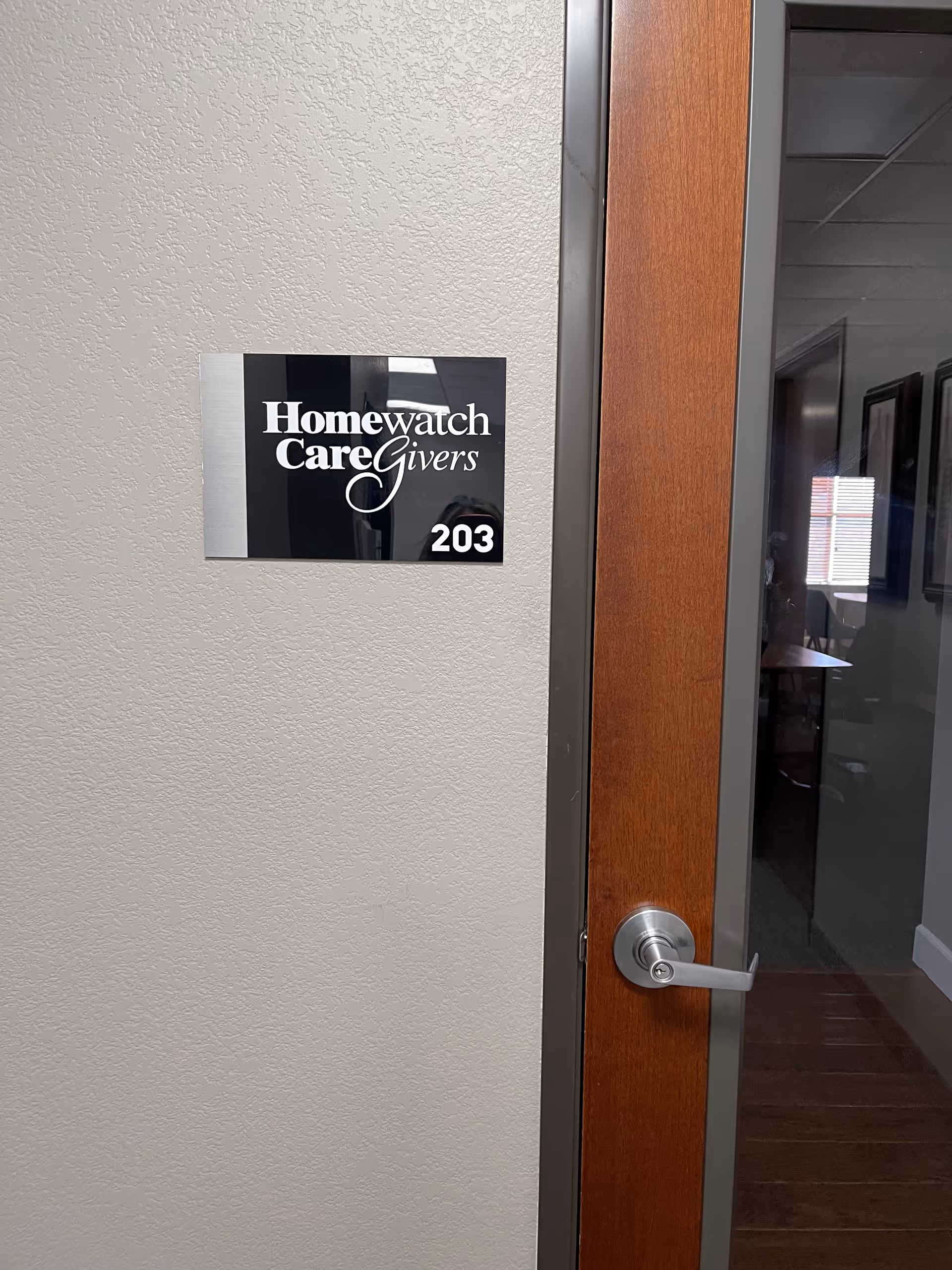 Interior doorway with a Homewatch CareGivers sign and room number 203.