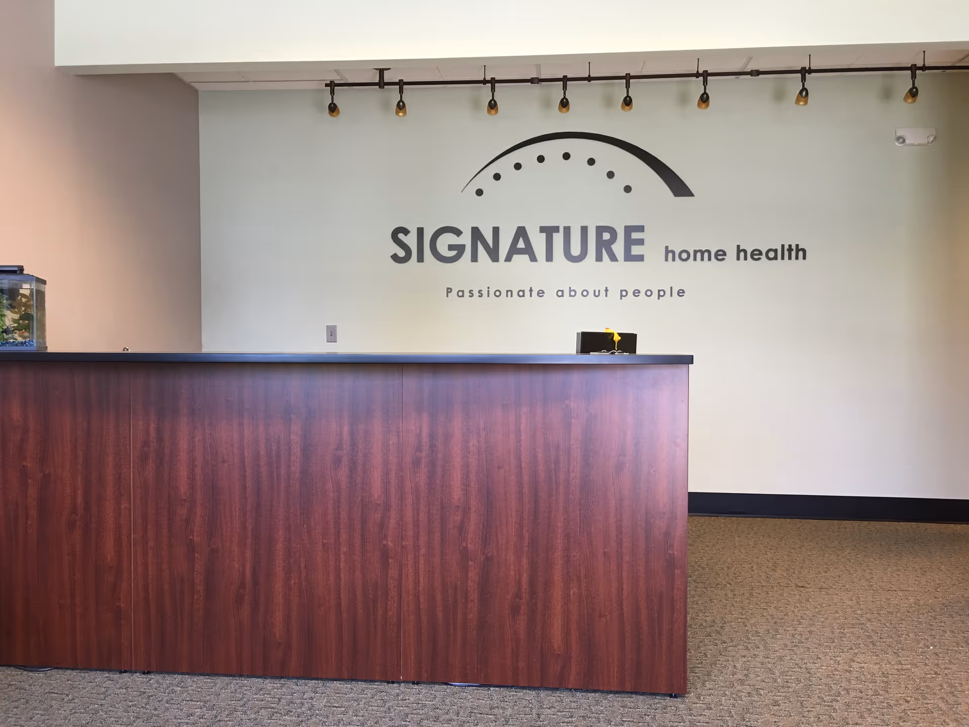 Front desk counter in a lobby with Signature home health logo on the wall.