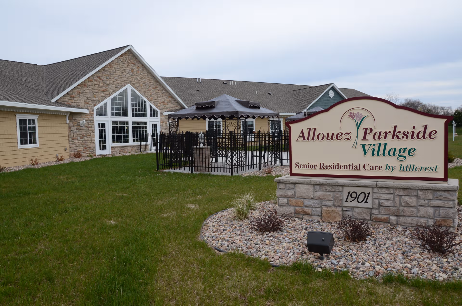 Exterior view of Allouez Parkside Village building with sign and outdoor seating.