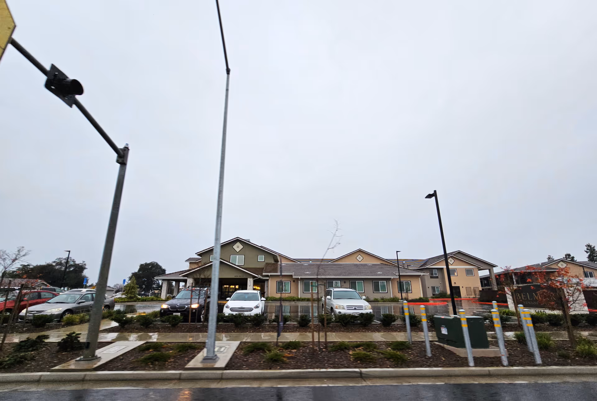 Belmar Senior Living exterior with a parking lot, low-rise building, and landscaped front under cloudy sky.