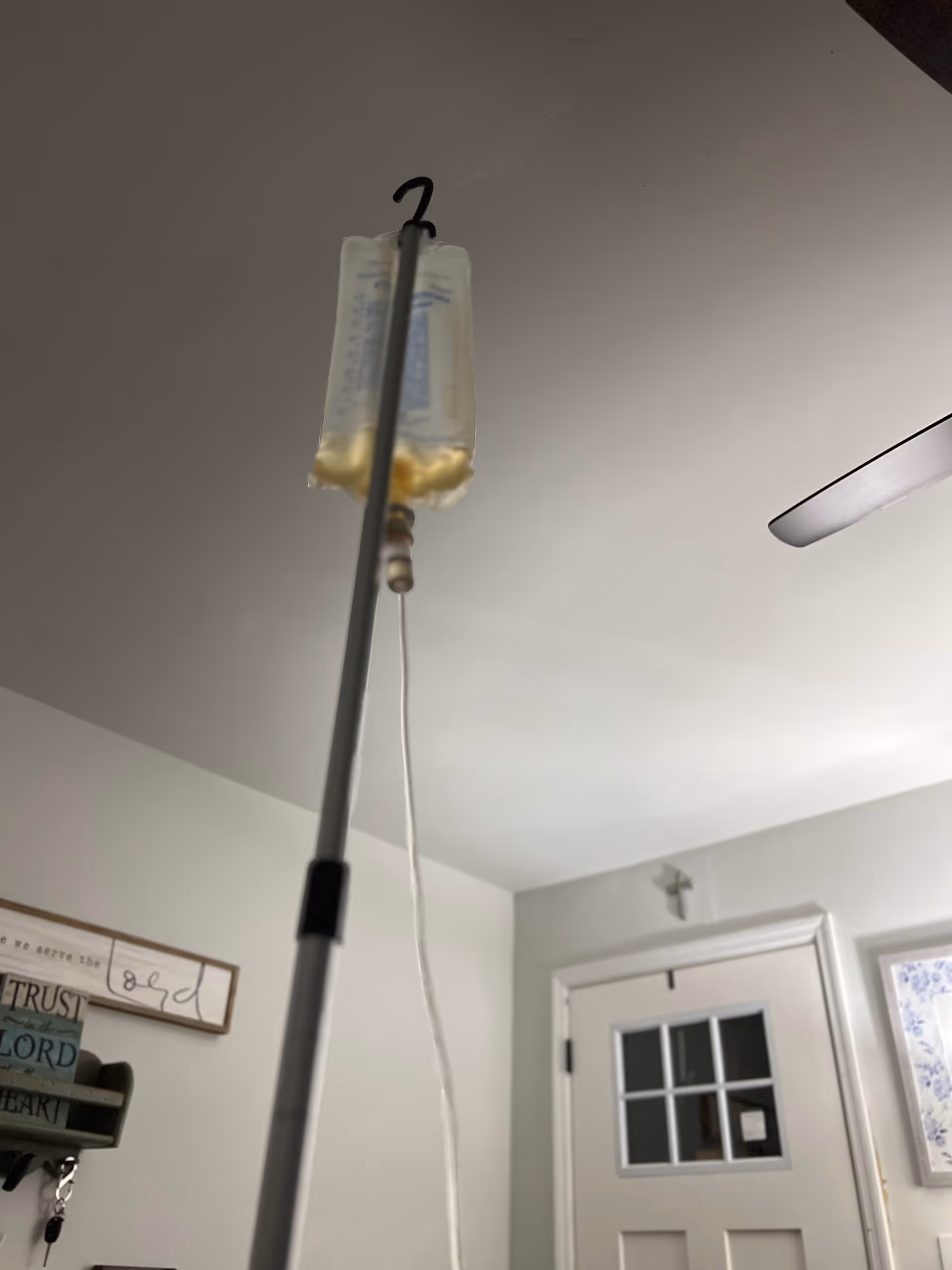 IV bag on a stand hanging from the ceiling in a clinical room.