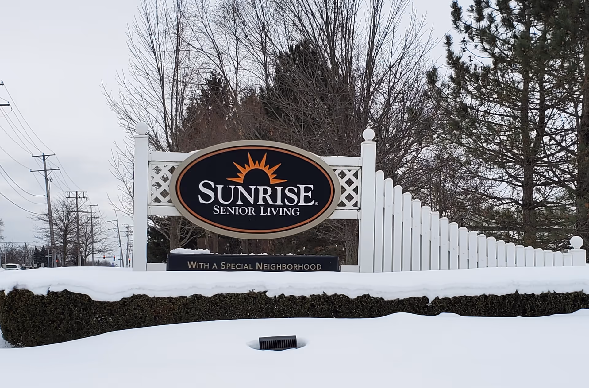 Snowy landscape with Sunrise Senior Living sign and stylized sun logo
