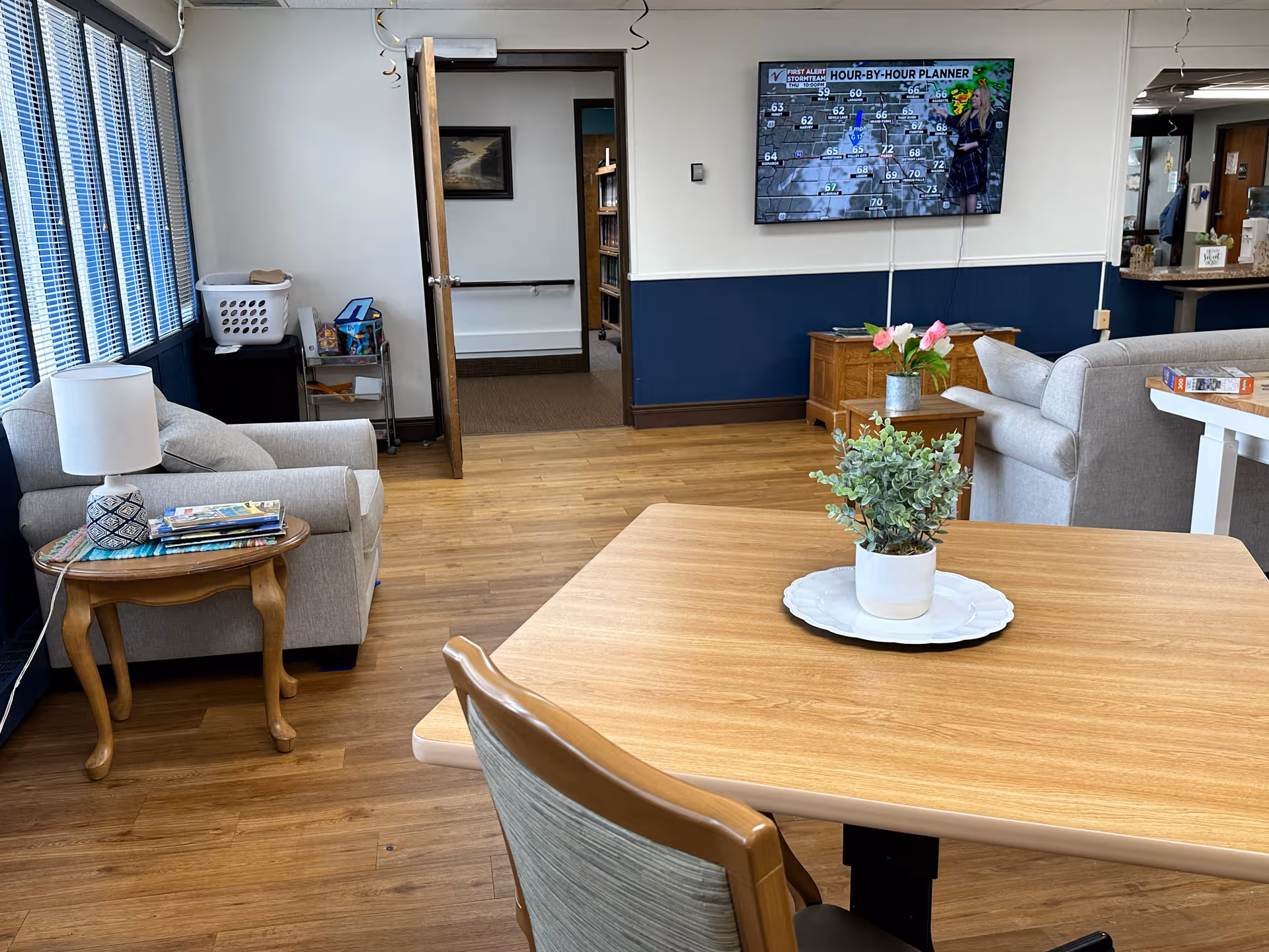 Common lounge area with couches, a TV, plants, and a wooden table.