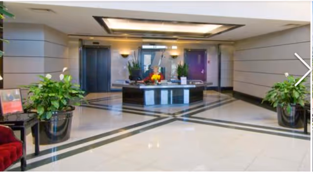 Modern hotel-style lobby with a circular reception desk and potted plants.