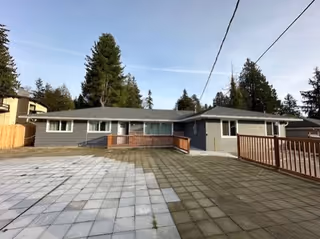 Single-story gray building with a wheelchair ramp and wooden railings at the front.